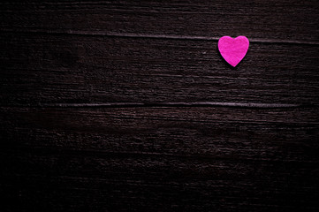 Little pink heart over dark-brown wooden background