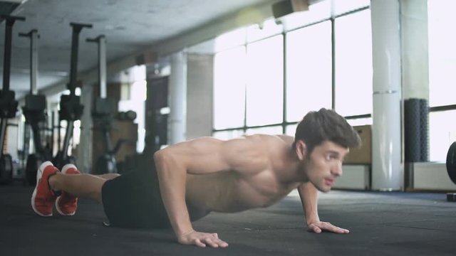 Handsome fitness man doing push ups in gym

