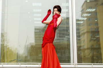 Beautiful woman in red dress on the background of a large window