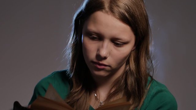 Teen girl is surrounded by books and reading. 4K UHD.