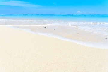 Fototapeta na wymiar A wave washing over the sandy seashore of a white sandy beach in Bali on a beautiful day