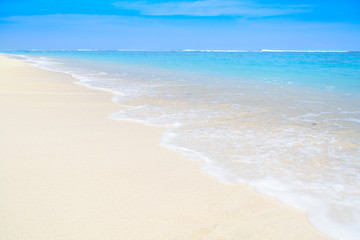 Fototapeta na wymiar A wave washing over the sandy seashore of an amazing tropical beach in Indonesia