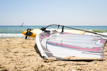 Windsurfing board with sail lying on the sand