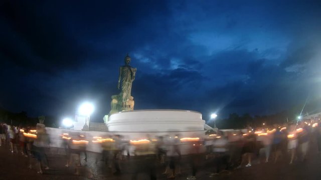 People walk with candles around a large Buddha statue to celebrate Visakha Bucha Day