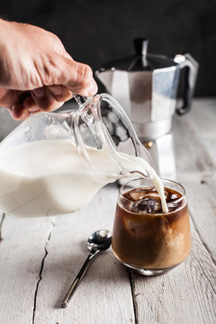 Close up of man's hand pouring milk into coffee cup