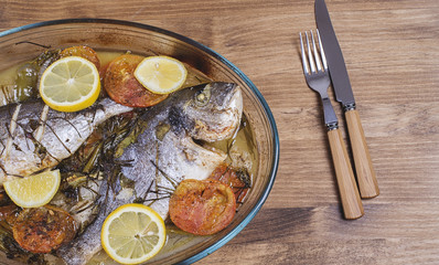Baked fish with carrot,lemon and greenery.From above