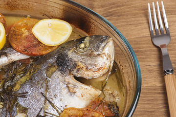 Baked fish with carrot,lemon and greenery.From above
