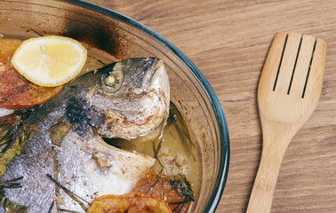 Baked fish with carrot,lemon and greenery.From above