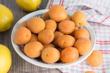 Naklejka na ściany i meble Fresh organic apricots in glass bowl on wooden board