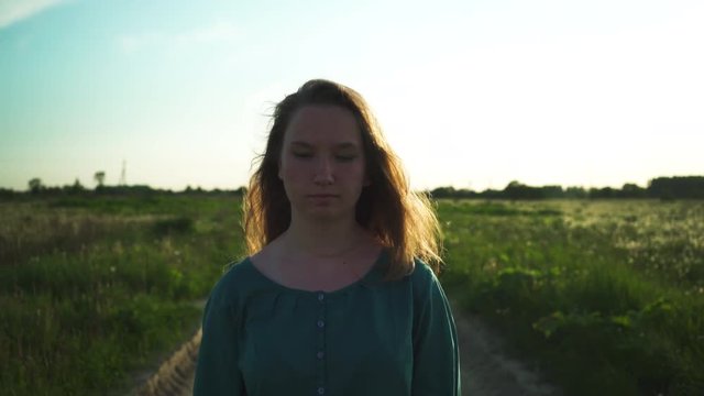 teen girl walking on old road near fields in sunset to camera shot with stabilizer