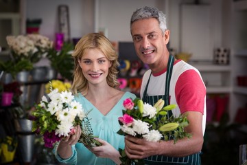 Smiling florists holding bunch of flowers in flower shop