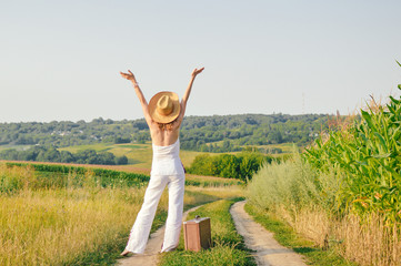 Fototapeta premium Elegant lady holding suitcase, countryside road outside background