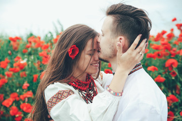 Lovely couple in the poppy field. Ukrainian traditional clothes