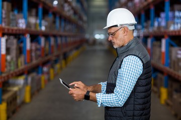 Side view of serious worker is using a tablet