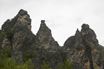 Fototapeta premium Eroded rocks in mountains against gray cloudy sky background