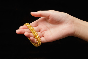 Girl's hands with golden bracelets on a black background
