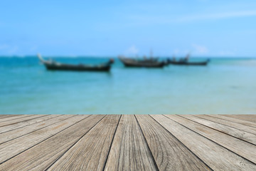 Wood table top with blurred nature scene tropical beach and long tail boat