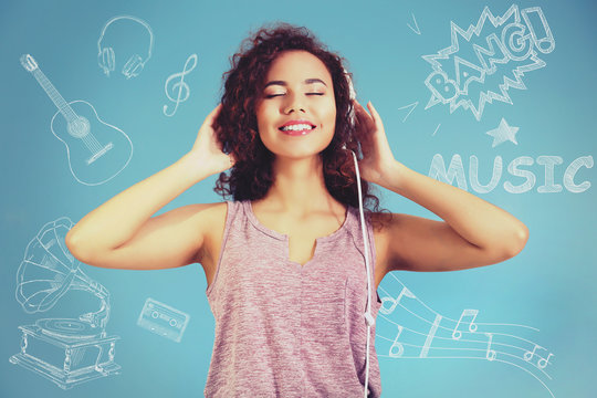 African American woman listening to music in headphones on blue background