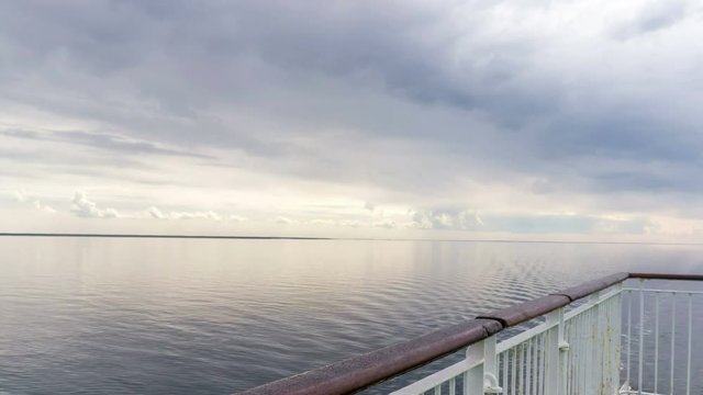 Time lapse backdrop of moody sky in the evening with still water on a boat deck
