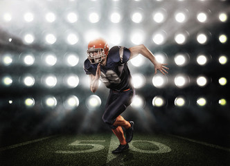 Naklejka premium Football player in blue uniform on grass illuminated by floodlights