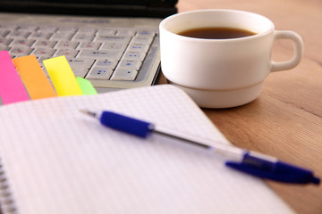 Office table with blank notepad and laptop
