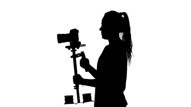 Videographer makes shooting around itself. White. Silhouette