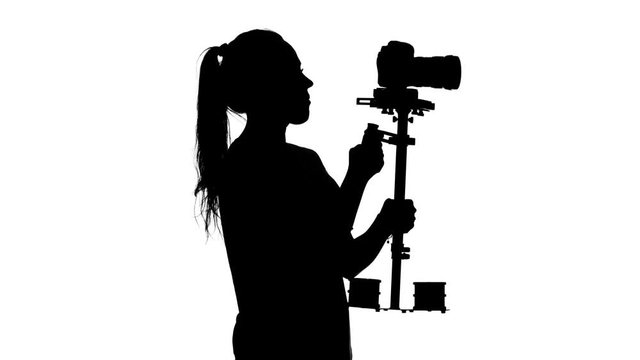 Operator shoots video in the studio. White. Silhouette