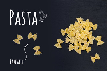 Uncooked Italian pasta Farfalle on black slate stone background with white lettering, top view