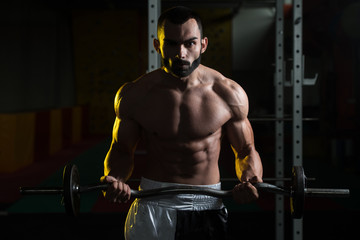 Obraz na płótnie Canvas Muscular Man Exercising Biceps With Barbell
