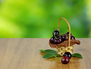 Basket of cherries on blurred natural background.