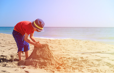 little boy play with sand on beach