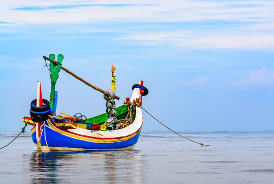 This a traditional style Indonesian fishing boat called a Jukung anchored up just of the shoreline early in the morning. 
