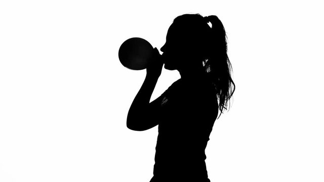 Girl is blowing a balloon. Silhouette. White