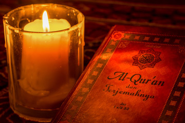 The holy Koran under the light of candles with only the cover illuminated.