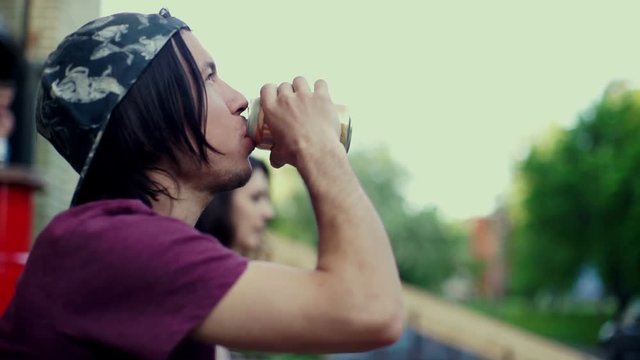 Young longboardist man drinking mineral water in the city