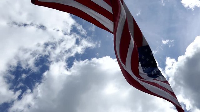 Birds flying over the waving national flag of United state of America with a sunny cloudy blue sky in background