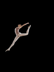 Beautiful ballerina posing in jump on black background