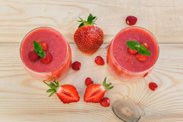 glass of strawberry smoothie on wooden table with mint