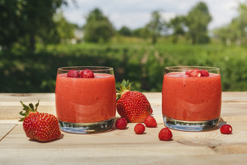 glass of strawberry smoothie on wooden table with mint