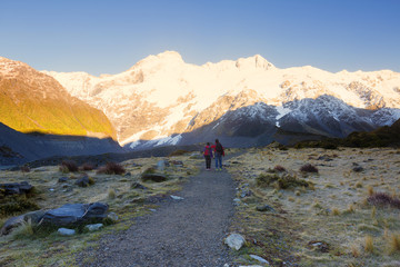 Obraz premium Hikers enjoying the moment mountain peaks illuminated by sun.