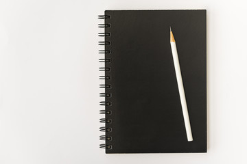 white pencil with black notebook on white