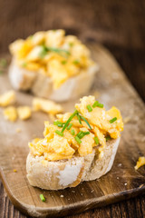 Wooden table with Scrambled Eggs on a bun (selective focus)