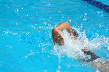 Asian teen swimmer practice forward crawl in a swimming pool for competition, rear side view