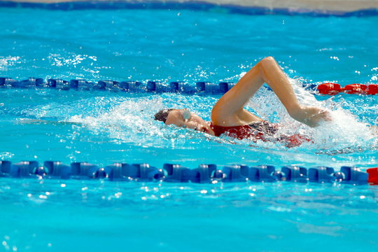 Asian teen swimmer wear black swimming cap swim in a swimming pool