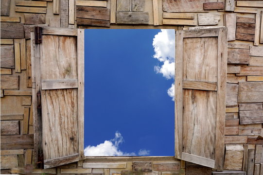 vintage style wooden window opening over view of blue sky and cloud background