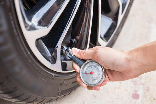 Close-Up Of Hand Holding Pressure Gauge For Car Tyre Pressure Measurement