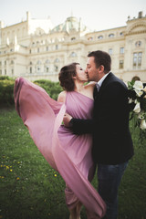 Naklejka premium Wedding. Couple. Krakow. The bride in a pink dress and groom posing on background of theater