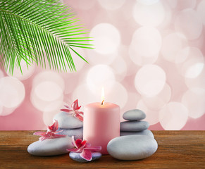 Fototapeta na wymiar Spa stones with burning candle and flowers on pink festive background