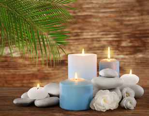 Fototapeta na wymiar Spa stones with burning candles and flowers on wooden background