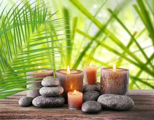 Spa stones with burning candles and flowers on natural background